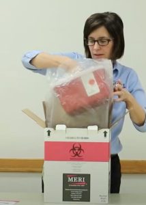 Woman removing sharps container from a mailback box